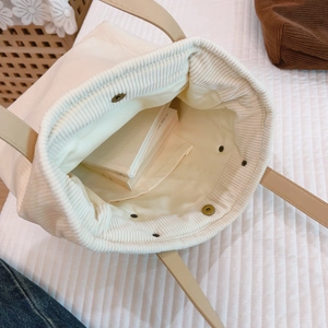 Minimalist beige corduroy tote bag with magnetic snap closure and leather straps