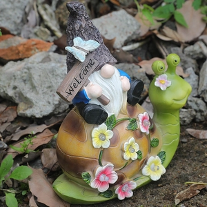 Solar powered garden gnome riding a green snail statue with LED flowers and Welcome sign