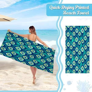 Detail of quick-drying microfiber beach towel with vibrant blue and green peacock print
