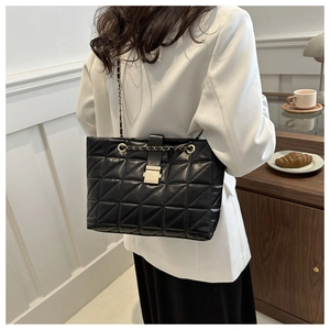 Détail du sac bandoulière matelassé noir avec chaîne dorée et fermeture à rabat