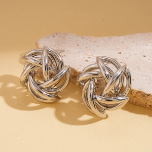 Macro view of silver geometric hollow flower knot stud earrings on a stone base