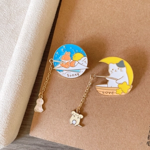 Détail de broches en émail chat et renard avec chaînes sur un carnet brun