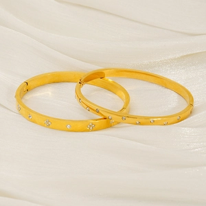 Detail of 18k gold plated stainless steel bangles with zircon clover pattern on silk