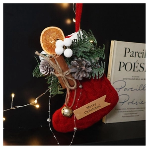 Macro shot of red knit Christmas stocking with pine cones, cinnamon sticks and tiny bells