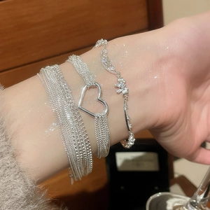Detail of layered silver heart bracelet with cubic zirconia charms on female wrist
