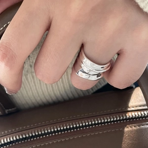 Lifestyle shot of wide sterling silver ring with irregular wave pattern on hand