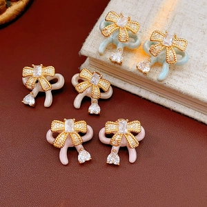 Detail of colorful enamel bow earrings with gold plating and sparkling zircon stones