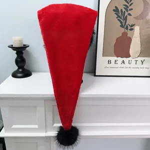 Plush red Christmas hat with unique black pompom displayed on a white fireplace mantle