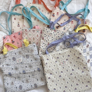 Flat lay of diverse floral and bear pattern canvas tote bags on white bedding