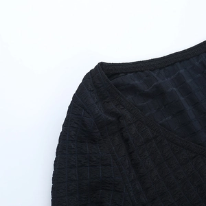 Close-up of black textured fabric and detailed stitching on backless long sleeve top