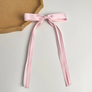 Pink satin bow hair clip with long ribbons on a minimalist white background