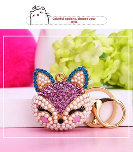 Close-up of fox head keychain with white pearls, pink and blue rhinestones on gold base