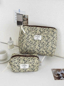 Dettaglio di due pochette in velluto a coste trapuntato a fiori con zip e nastri