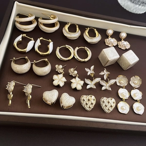 Flat lay of vintage pearl and gold flower, heart, and butterfly earrings on a display tray