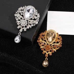 Detailed view of silver and gold vintage brooches with pear-shaped crystals on gift box