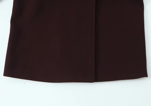 Close-up of soft burgundy wool coat hem and placket showing premium stitching details