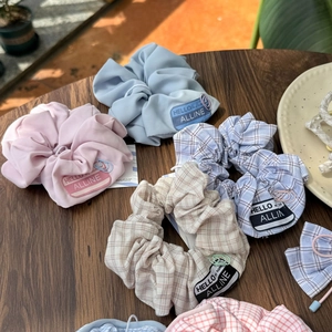 Detailed shot of bow-style scrunchies with fabric labels and colorful paperclip accents