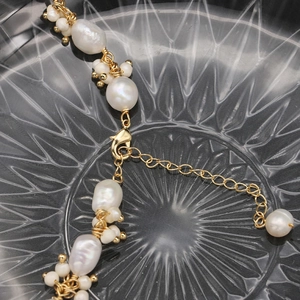 Baroque natural pearl necklace with irregular white beads and gold accents on glass