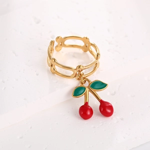 Close-up of gold cherry pendant ring with red glaze fruit and green enamel leaf detail