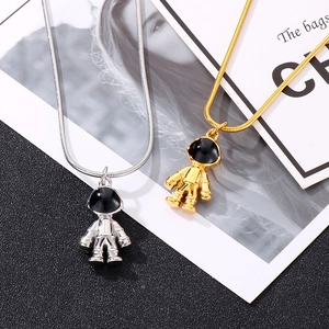 Detail of silver and gold astronaut pendants on snake chains over black background