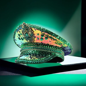 Close-up of green sequins, gold rivets, and a large central gem on a festive party hat