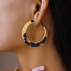 Gros plan de boucles d'oreilles créoles en C avec motif écailles de tortue et argent