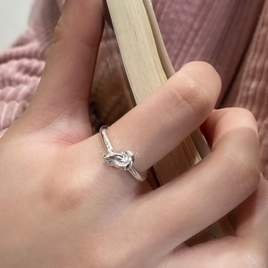 Dettaglio di un anello minimalista con nodo in argento indossato da una modella