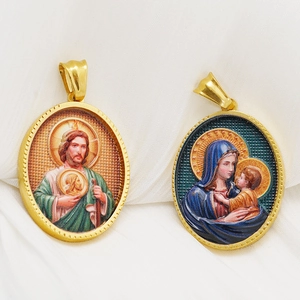 Detailed close-up of 18k gold-plated oval religious pendants on soft white fabric