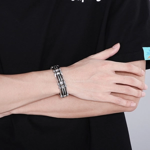 Close-up of industrial steel cable bracelet with black links on a male wrist