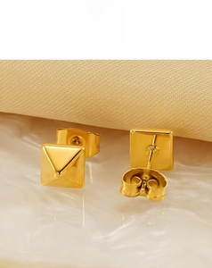 Vue macro de boucles d'oreilles pyramides en acier doré avec finition miroir poli