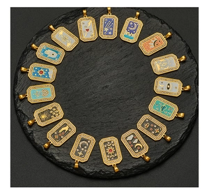 Macro detail of sixteen assorted gold enamel charms with celestial motifs on black stone