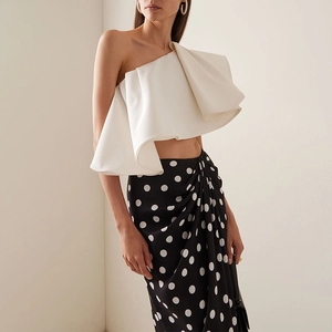 Detail of white one-shoulder ruffle top and black polka dot wrap skirt set for women