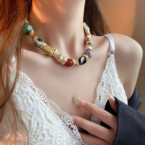 Close-up of ethnic ceramic flower necklace with colorful beads and gold twisted metal tubes
