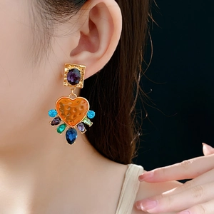 Gros plan de boucles d'oreilles cœur vintage dorées avec strass colorés sur un modèle