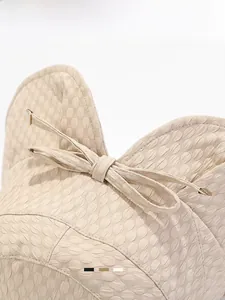 Close-up of beige sun hat with 3D honeycomb texture and elegant bow detail