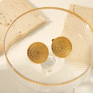 Macro d'élégantes boucles d'oreilles dorées rondes avec texture en spirale sur verre