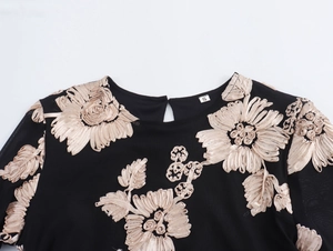 Detail van zwarte mesh jurk met champagnekleurig bloemenborduurwerk en bladpatronen