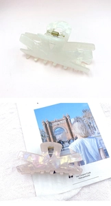 Detailed view of large pearlescent hair claws in cream white and light pink finish