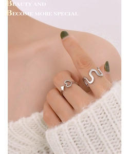Detail of silver wave and heart arrow open rings on model with white knit sweater