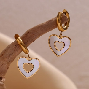 Macro shot of 18K gold heart earrings with white mother of pearl inlay on natural branch