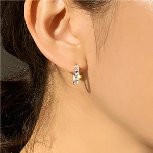Close-up of sparkling silver hoop earring with single row of cubic zirconia on ear
