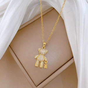 Macro shot of gold teddy bear pendant with crystal stones on elegant silk and jewelry box