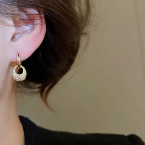 Golden textured oval drop earrings with vintage minimalist design on model close-up