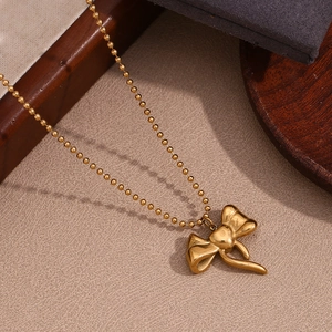 Detailed view of the 18K gold plated bow pendant on a delicate beaded ball chain necklace