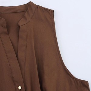 Detailed close-up of sleeveless dress featuring a V-neckline and gold button accent