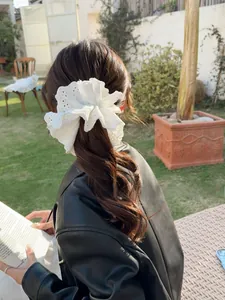 Detail of white heavy-duty lace scrunchie with intricate eyelet embroidery on low ponytail