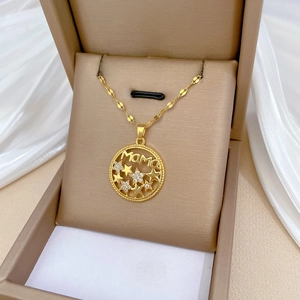Golden MAMA and star necklace with zircons in jewelry box on white silk background