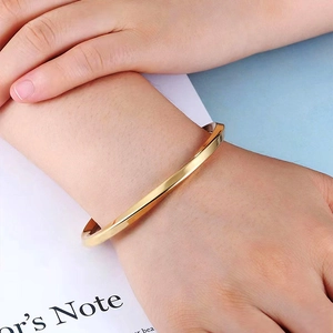 Close-up of polished gold Mobius twisted stainless steel bangle worn on a model's wrist