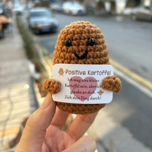 Handmade crochet positive potato doll held by hand with motivational German card text