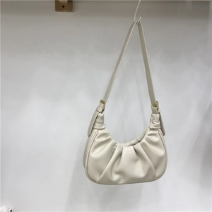 Detail of cream white pleated cloud bag with golden buckle and adjustable strap